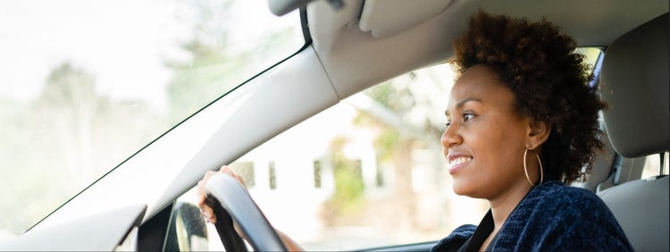 A woman looking happy while driving her car