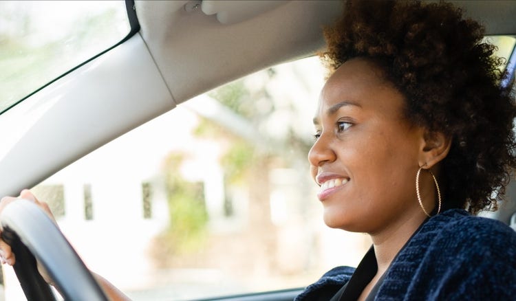 A woman looking happy while driving her car